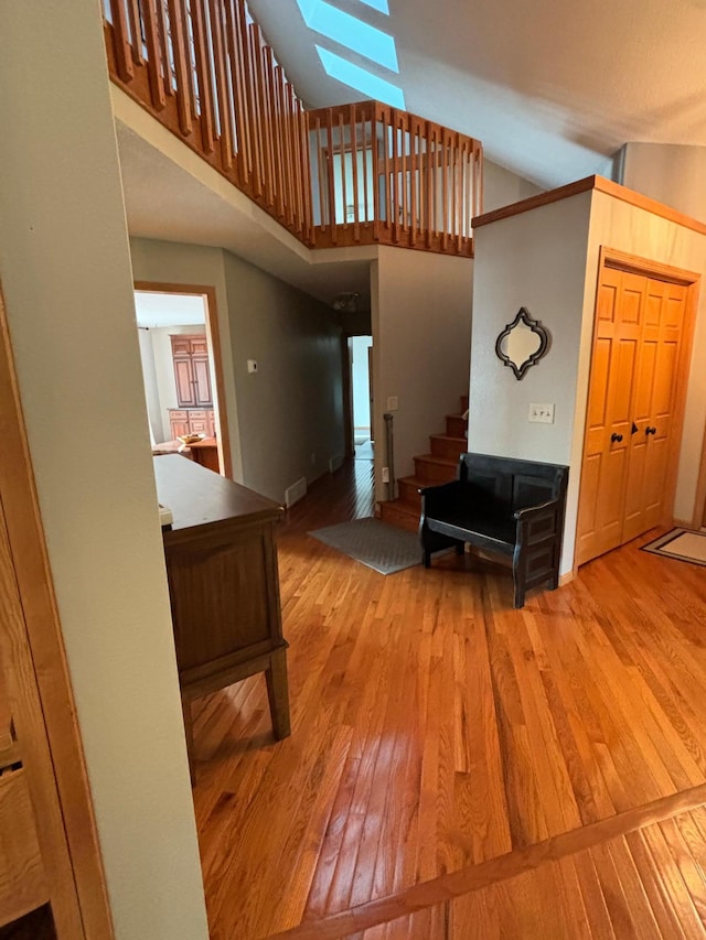 stairway featuring a high ceiling, wood-type flooring, and a skylight