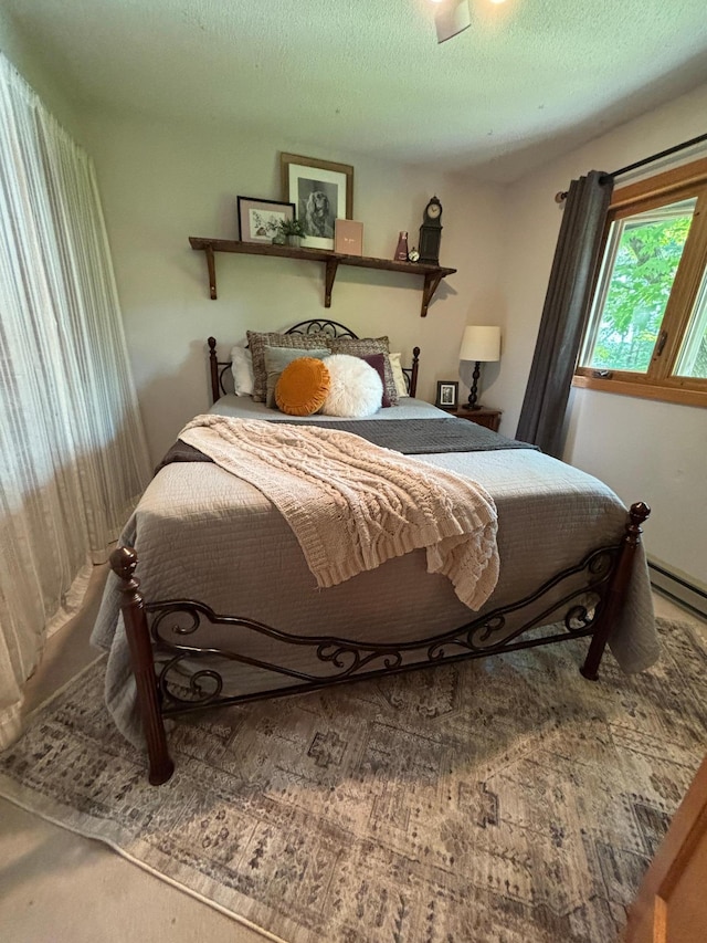 carpeted bedroom with a baseboard heating unit and a textured ceiling