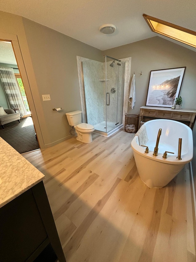 full bathroom featuring toilet, hardwood / wood-style floors, lofted ceiling with skylight, vanity, and shower with separate bathtub