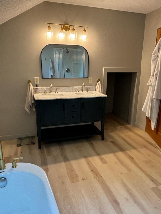 bathroom with vanity, a textured ceiling, independent shower and bath, and vaulted ceiling