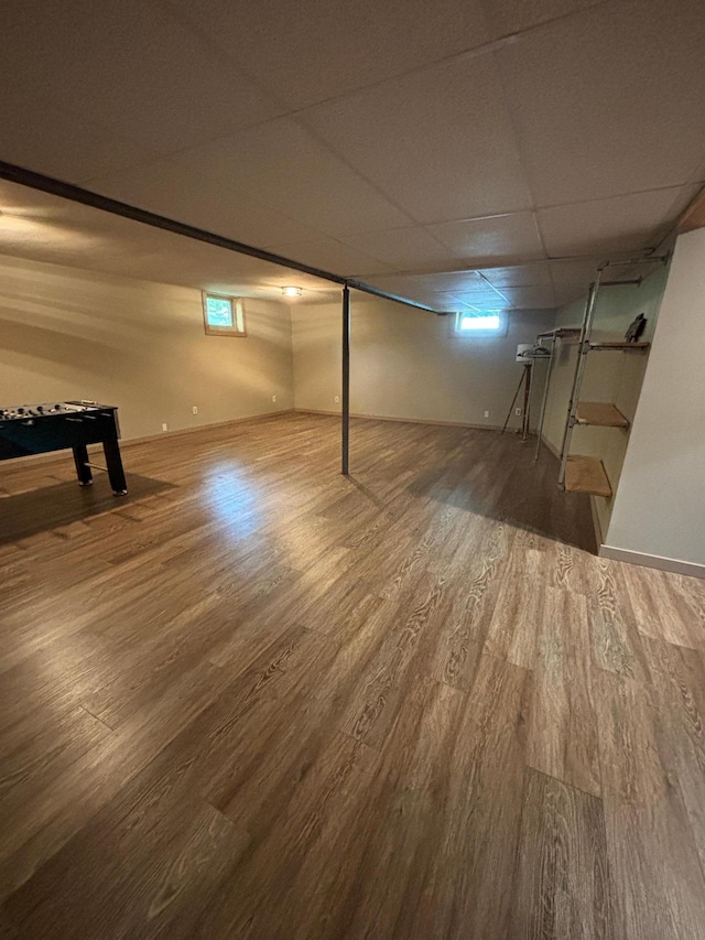 basement with a paneled ceiling and wood-type flooring