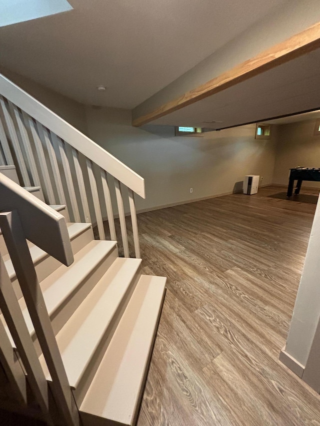 stairway featuring beamed ceiling and hardwood / wood-style floors