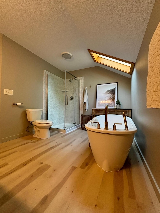 bathroom with vaulted ceiling with skylight, toilet, separate shower and tub, and a textured ceiling