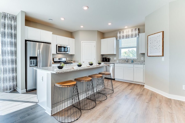 kitchen featuring white cabinetry, stainless steel appliances, a center island, and light hardwood / wood-style floors