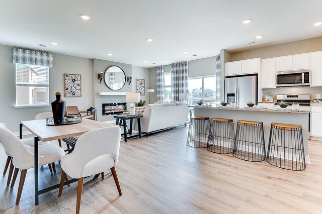 dining space with a wealth of natural light, a textured ceiling, and light hardwood / wood-style floors