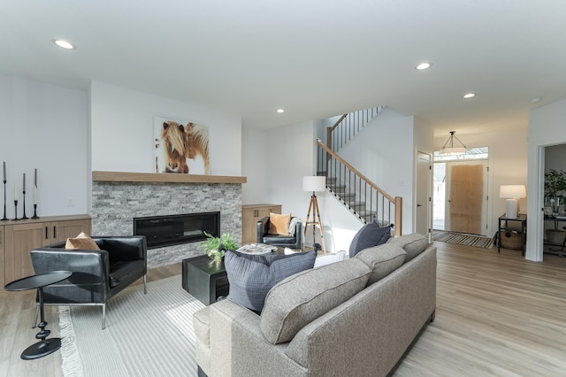 living room with light wood finished floors, a fireplace, stairway, and recessed lighting