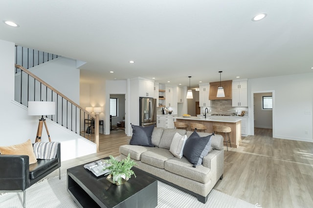 living area featuring baseboards, light wood finished floors, stairway, and recessed lighting