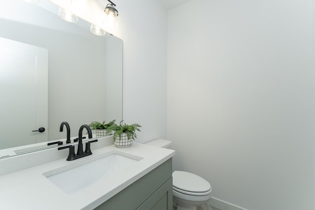 bathroom featuring baseboards, vanity, and toilet