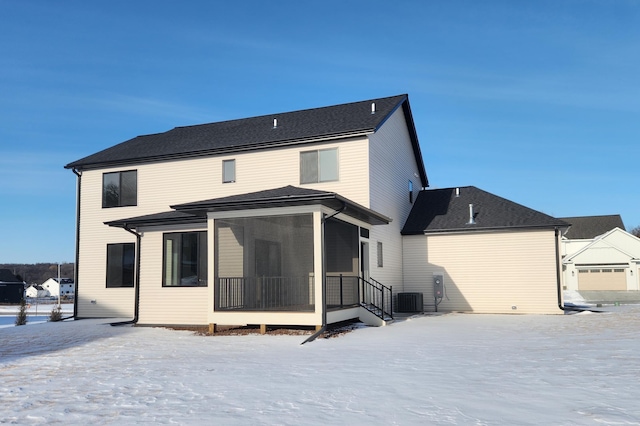 snow covered property featuring central air condition unit and a sunroom