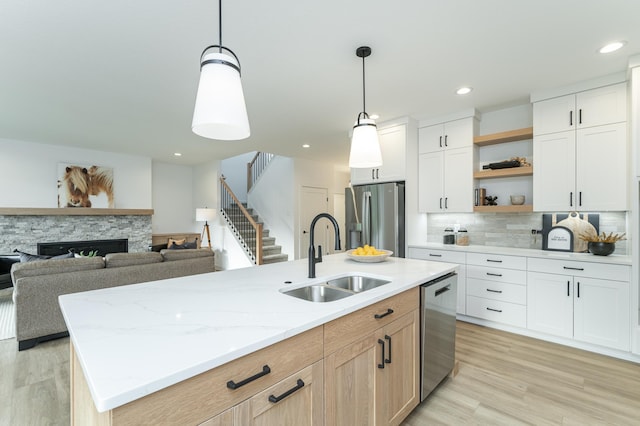 kitchen featuring decorative backsplash, stainless steel appliances, a stone fireplace, open shelves, and a sink