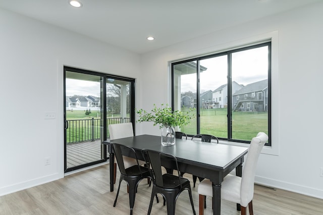 dining space featuring baseboards, recessed lighting, a residential view, and light wood-style floors