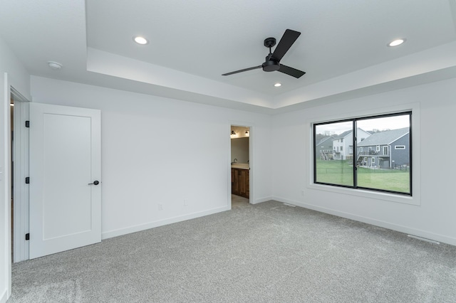 interior space featuring light carpet, recessed lighting, a raised ceiling, and baseboards