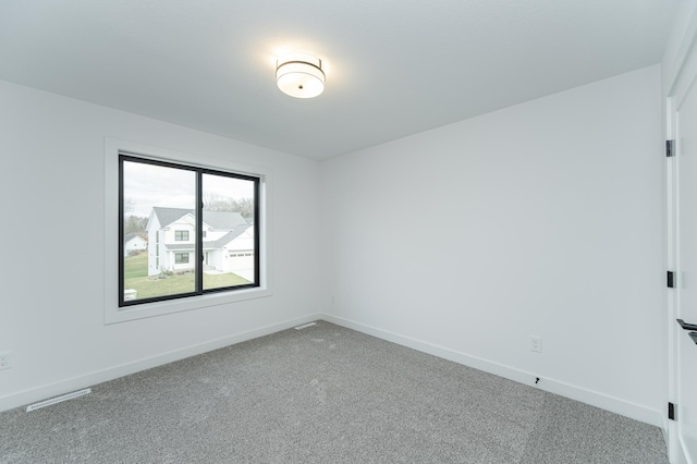 spare room with carpet floors, visible vents, and baseboards