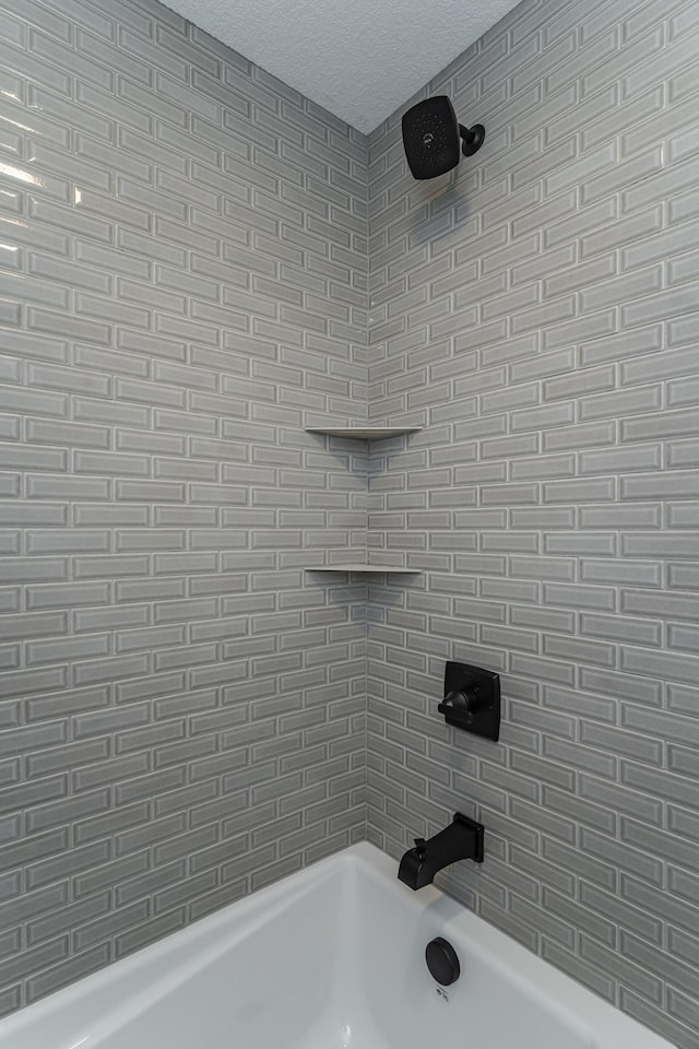 bathroom with shower / bath combination and a textured ceiling