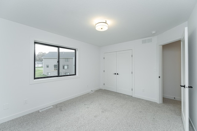 unfurnished bedroom featuring carpet floors, baseboards, visible vents, and a closet