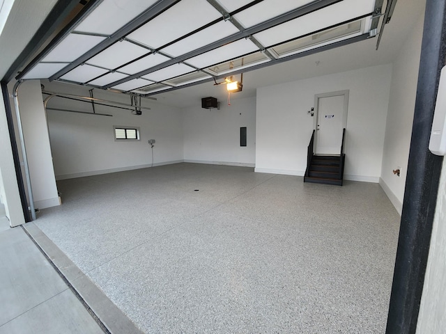 garage with a garage door opener, electric panel, and baseboards