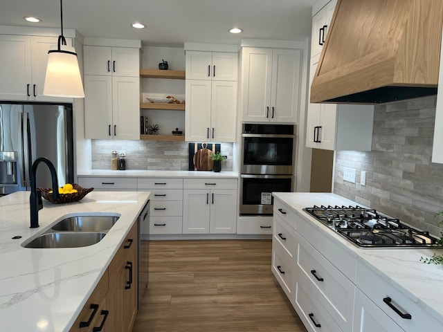 kitchen featuring custom exhaust hood, open shelves, stainless steel appliances, white cabinets, and a sink