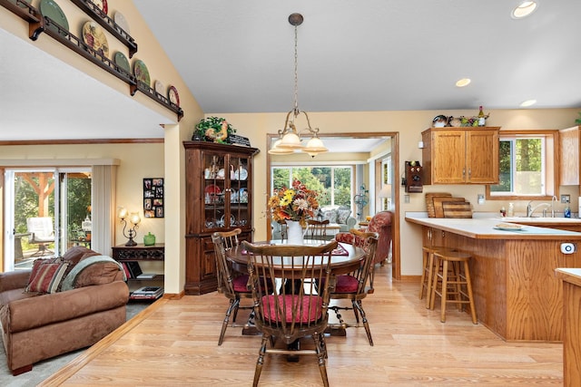 dining area with vaulted ceiling, sink, and light hardwood / wood-style flooring