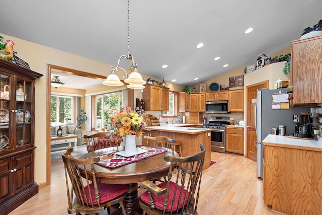 dining space featuring sink, light hardwood / wood-style floors, a notable chandelier, and vaulted ceiling