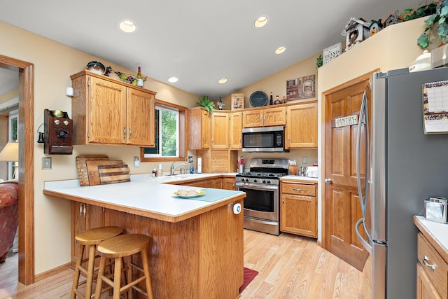 kitchen featuring light hardwood / wood-style floors, stainless steel appliances, sink, kitchen peninsula, and lofted ceiling