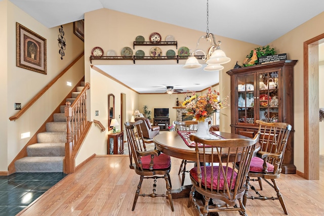 dining area featuring ceiling fan with notable chandelier, vaulted ceiling, and light hardwood / wood-style flooring