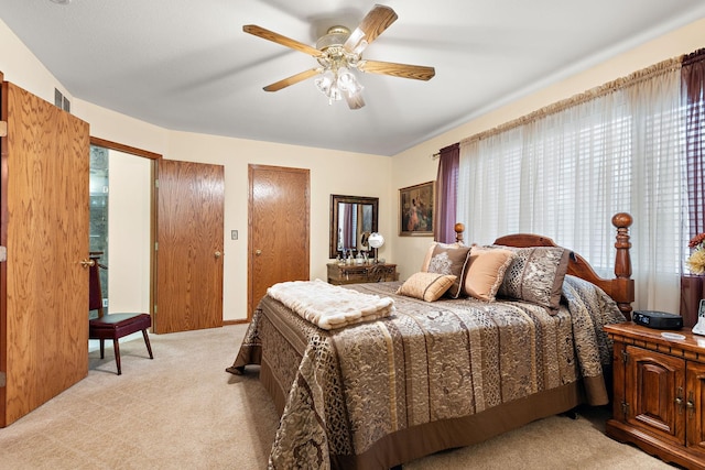 carpeted bedroom featuring ceiling fan, multiple closets, and multiple windows