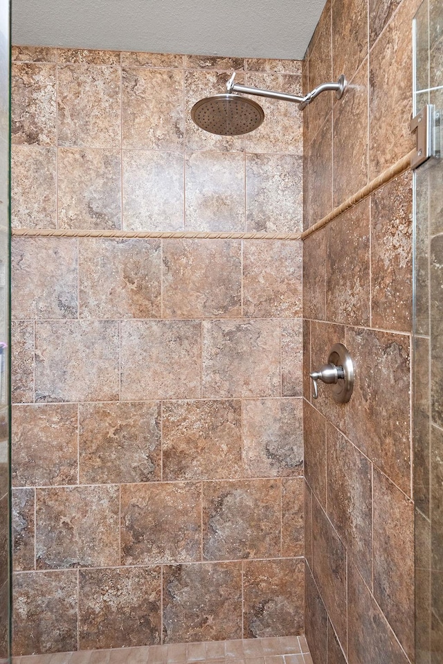 interior details with a textured ceiling and tiled shower