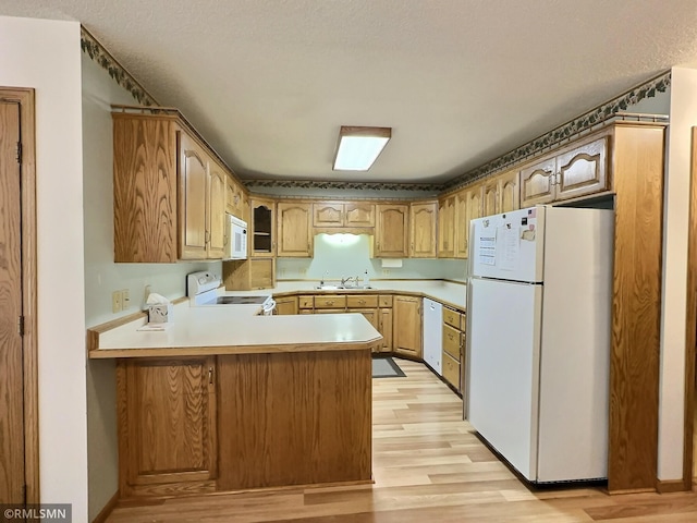 kitchen with sink, light hardwood / wood-style flooring, kitchen peninsula, a textured ceiling, and white appliances