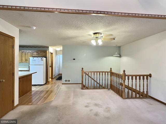 carpeted spare room featuring ceiling fan and a textured ceiling