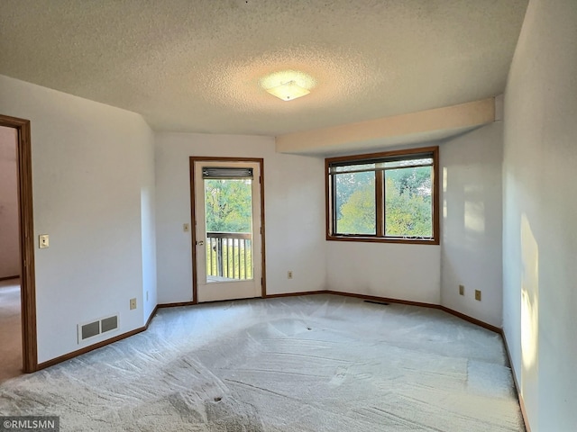 carpeted empty room featuring a textured ceiling