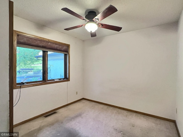 carpeted empty room featuring ceiling fan and a textured ceiling