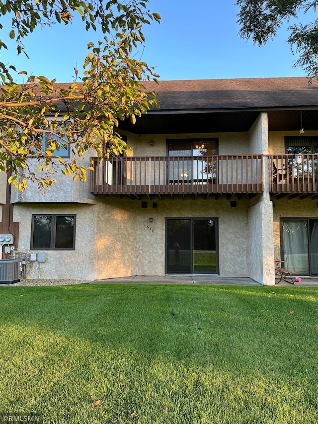 rear view of property featuring a yard, a balcony, and central AC unit