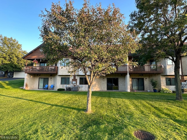 rear view of house featuring a lawn, a balcony, and central AC unit