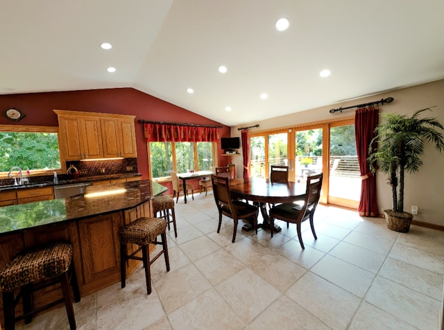 dining room featuring light tile patterned flooring, a healthy amount of sunlight, vaulted ceiling, and sink