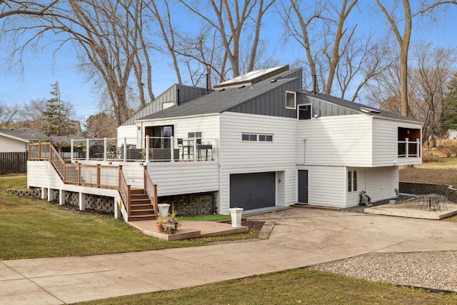 back of property with a lawn, a garage, and a deck