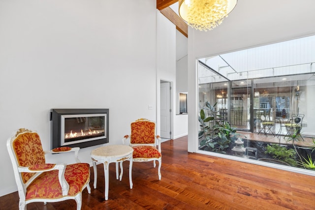 sitting room featuring wood-type flooring, an inviting chandelier, high vaulted ceiling, and beam ceiling