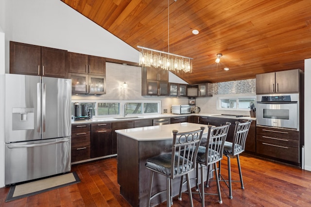 kitchen featuring dark brown cabinets, stainless steel appliances, dark wood-type flooring, sink, and a center island