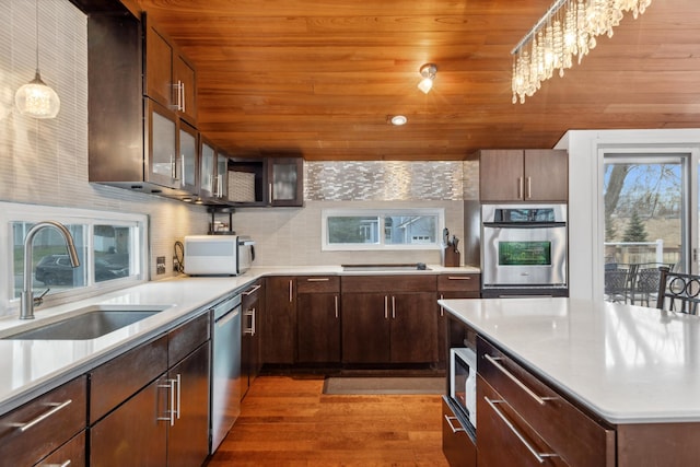 kitchen featuring appliances with stainless steel finishes, dark wood-type flooring, sink, decorative light fixtures, and a notable chandelier