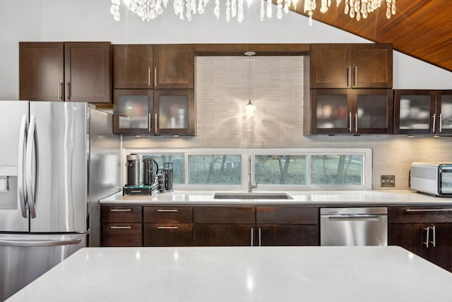 kitchen featuring sink, pendant lighting, lofted ceiling, decorative backsplash, and appliances with stainless steel finishes