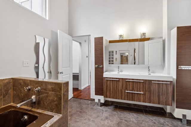 bathroom featuring a bath, a high ceiling, vanity, and tile patterned floors