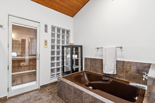 bathroom featuring tiled bath, tile patterned flooring, wooden ceiling, and lofted ceiling