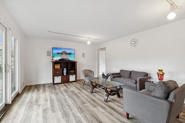 living room featuring rail lighting and light hardwood / wood-style flooring