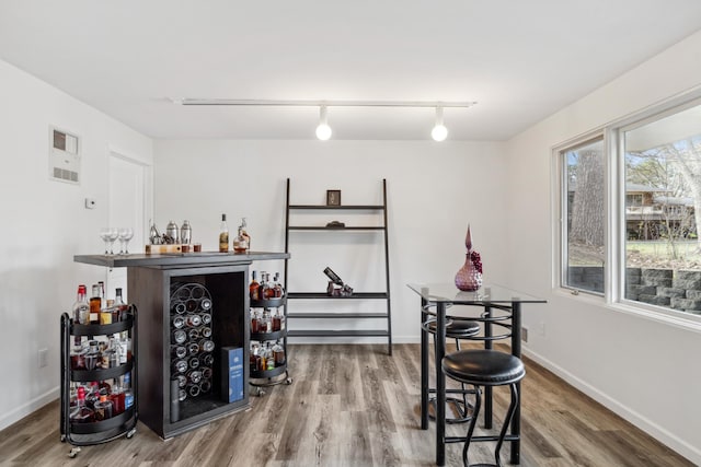 bar with wood-type flooring and track lighting