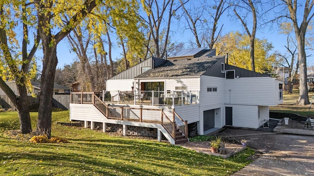 back of property featuring a deck and a lawn