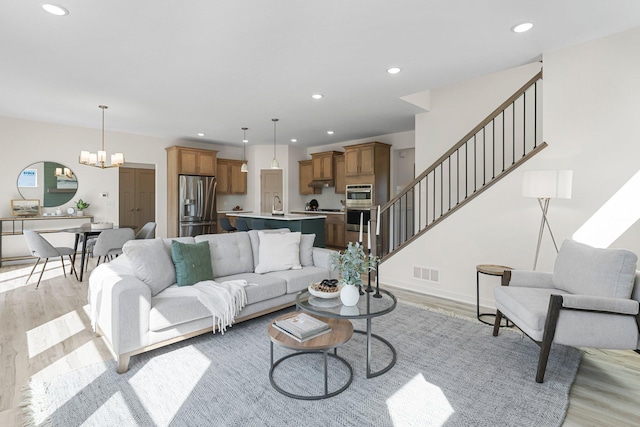 living room featuring a chandelier, light wood-type flooring, and sink