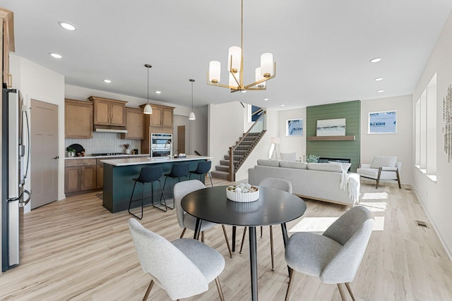 dining space featuring an inviting chandelier, a fireplace, and light hardwood / wood-style flooring