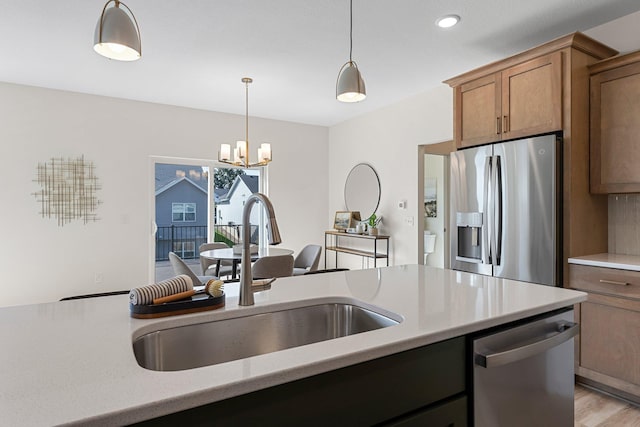 kitchen featuring sink, decorative light fixtures, appliances with stainless steel finishes, a notable chandelier, and light hardwood / wood-style floors