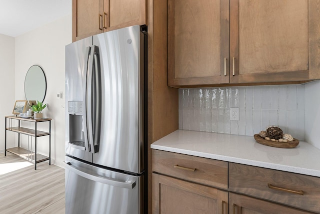 kitchen with decorative backsplash, light hardwood / wood-style floors, and stainless steel fridge with ice dispenser