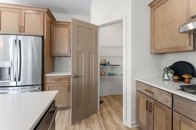 kitchen featuring tasteful backsplash, exhaust hood, appliances with stainless steel finishes, and light hardwood / wood-style flooring