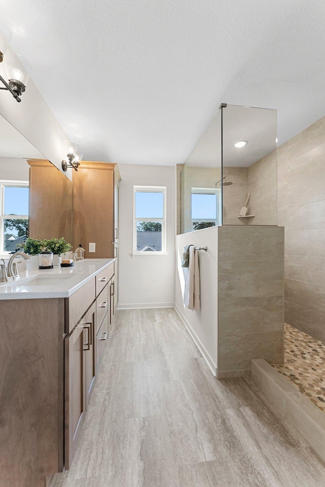 bathroom with vanity, a textured ceiling, tiled shower, an inviting chandelier, and hardwood / wood-style floors